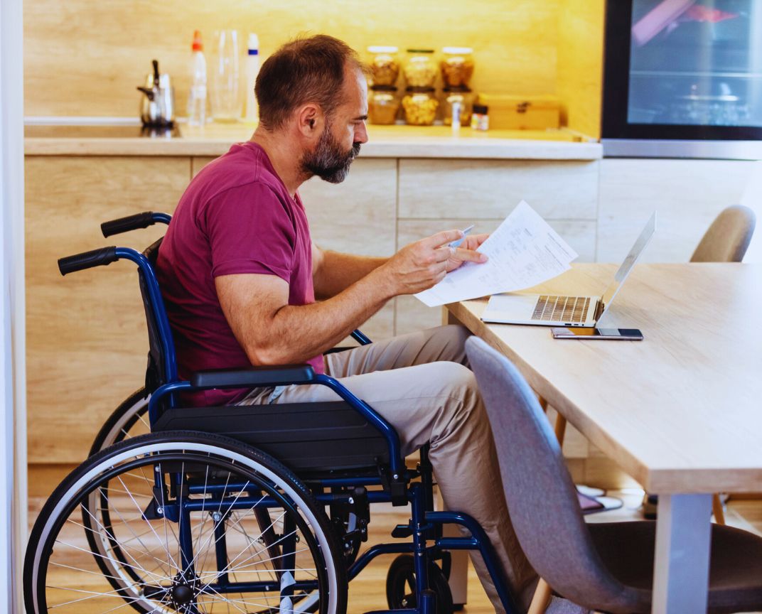 Financial Adviser South East Melbourne – person in wheelchair reviewing documents at the table